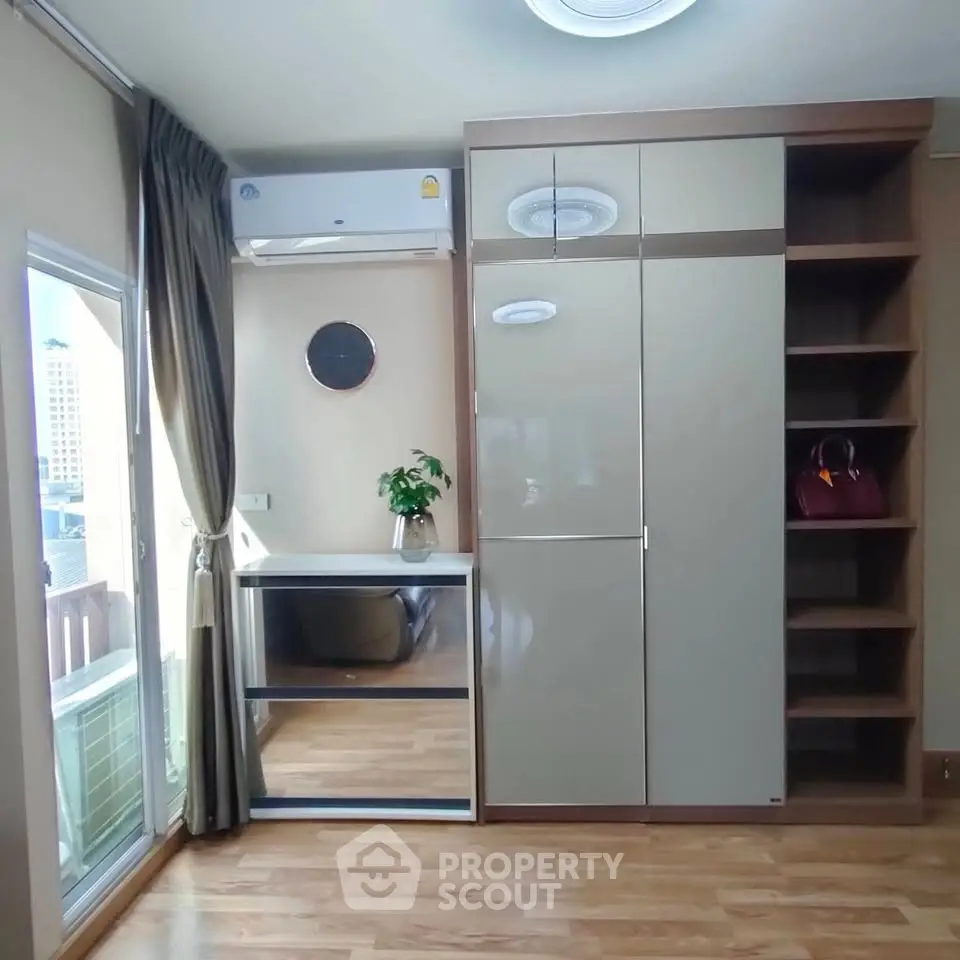 Modern bedroom with large wardrobe and city view window, featuring sleek wooden flooring and stylish decor.