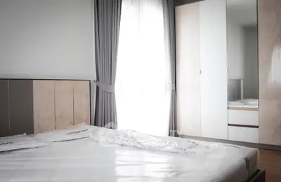 Modern bedroom with sleek wardrobe and natural light through large window.