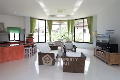 Spacious living room with modern furniture and large windows offering garden views.