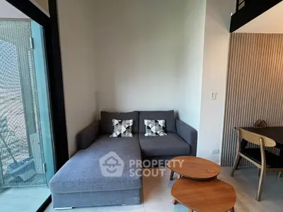Modern living room with stylish gray sofa and wooden coffee tables, featuring a cozy and inviting atmosphere.