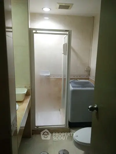 Compact bathroom with shower and washing machine in modern apartment
