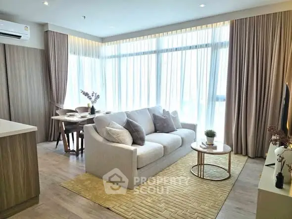 Modern living room with large windows, cozy sofa, and elegant decor in a bright apartment.