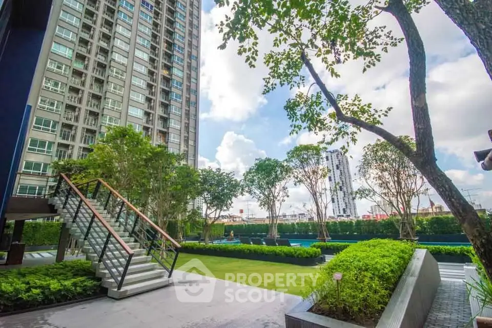 Modern high-rise building with lush garden and outdoor seating area, perfect for urban living.