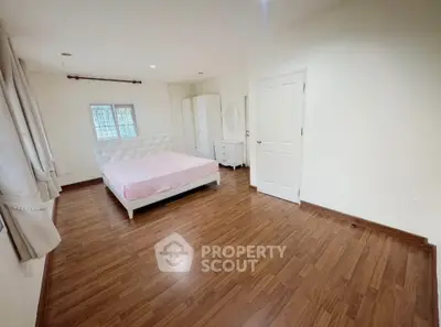 Spacious bedroom with wooden flooring and elegant white furniture