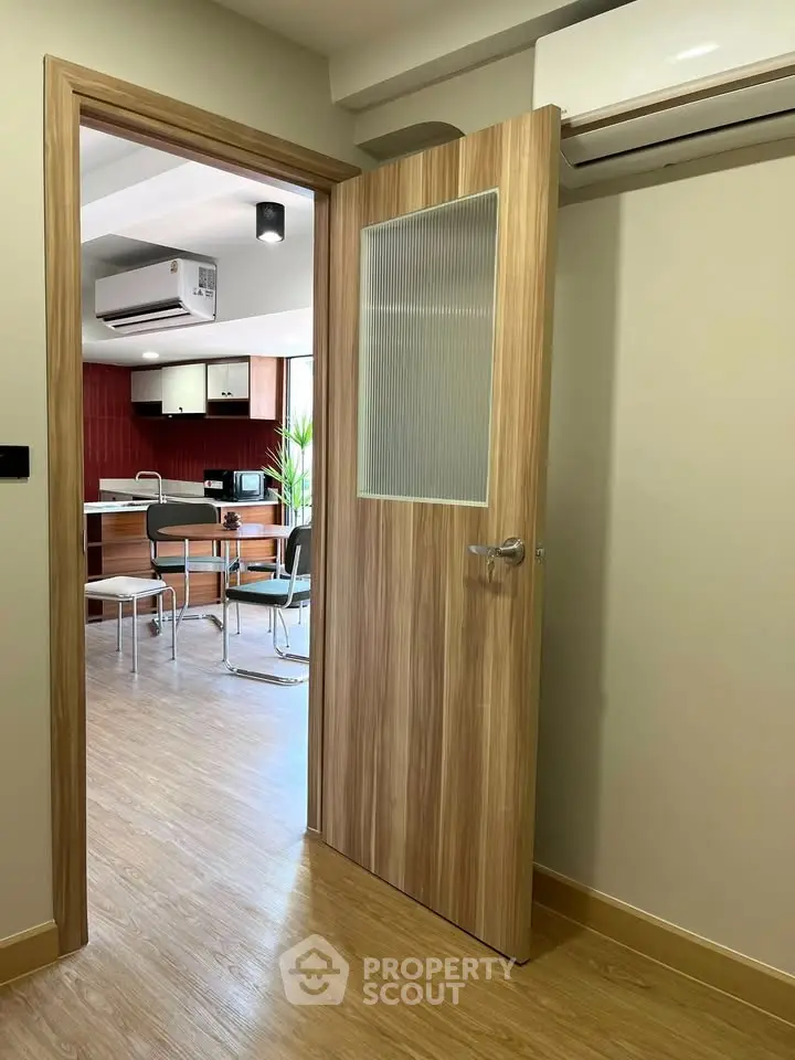 Modern kitchen with open layout and wooden flooring, featuring air conditioning and dining area.