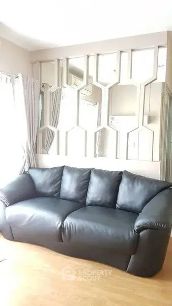 Stylish living room with modern black leather sofa and decorative wall mirrors.
