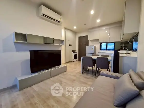 Modern living room with open kitchen, sleek furniture, and cozy ambiance.