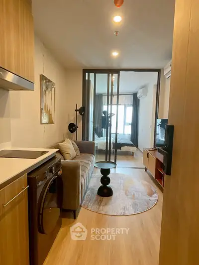 Modern apartment with open layout, featuring cozy living room and stylish bedroom separated by glass doors.