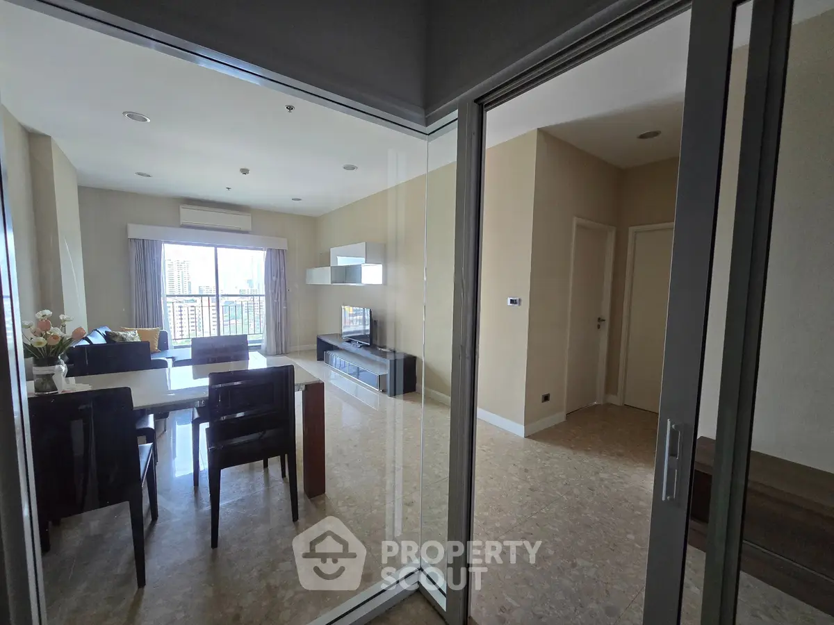 Spacious modern living room with dining area and large windows offering city views.