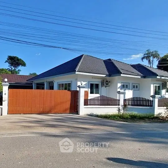 Charming single-story house with modern roof and wooden gate in a serene neighborhood.