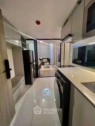 Modern kitchen with sleek appliances and open layout leading to stylish living area.
