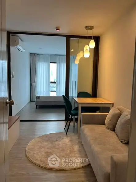 Modern living room with cozy sofa and dining area, leading to a bright bedroom with large windows.