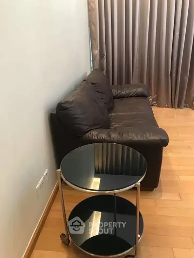 Cozy living room with leather sofa and modern side table, perfect for relaxation.