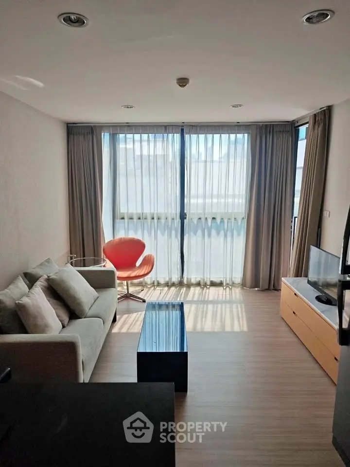 Modern living room with large windows, stylish furniture, and abundant natural light.