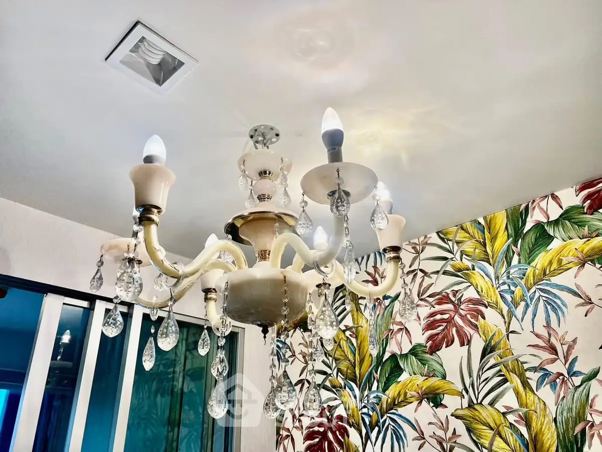 Elegant chandelier with crystal accents in a vibrant, tropical-themed room.