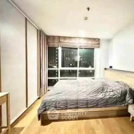 Spacious bedroom with large window offering stunning city views and modern decor.