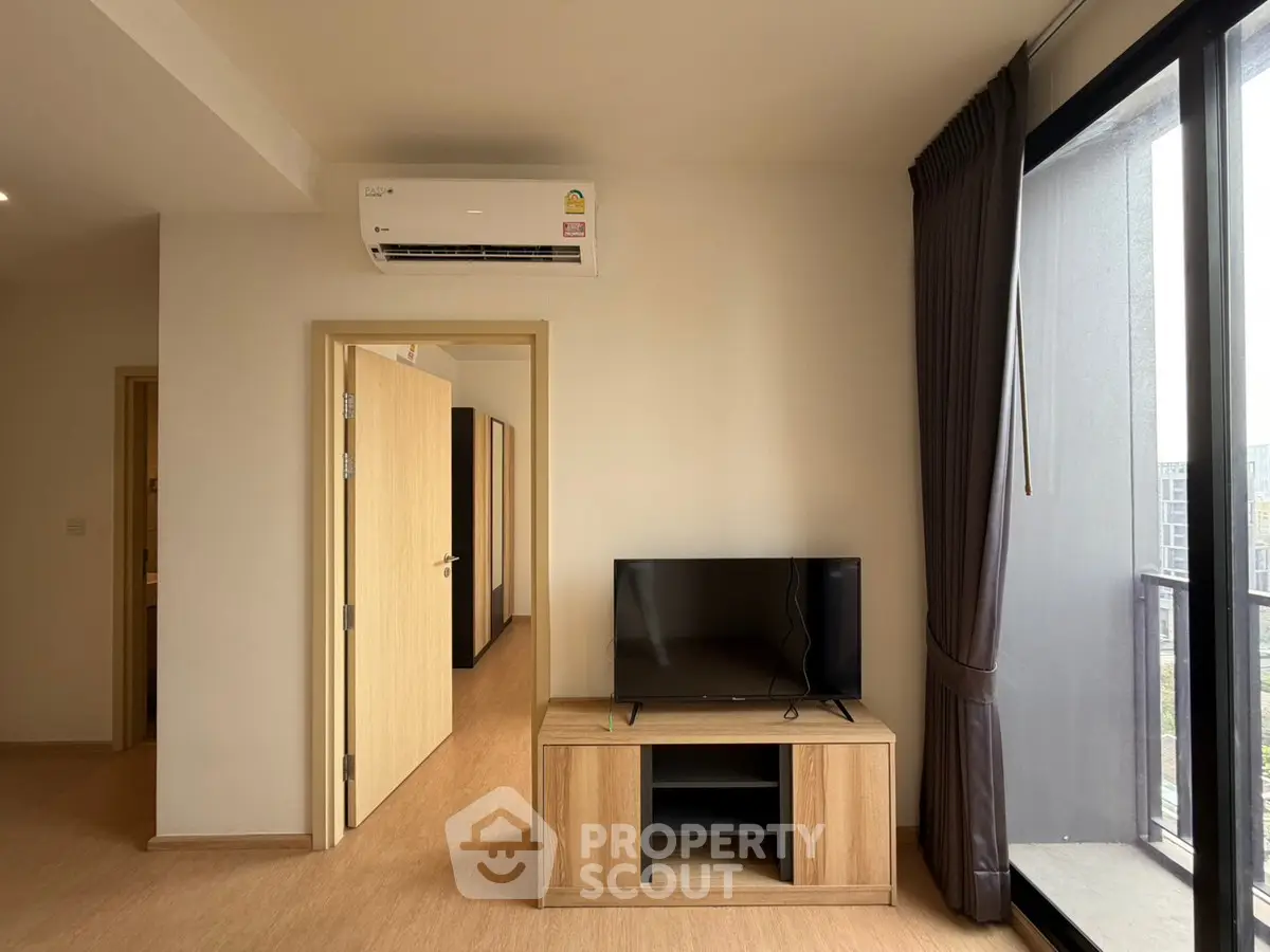 Modern living room with TV and air conditioning, featuring a balcony view.