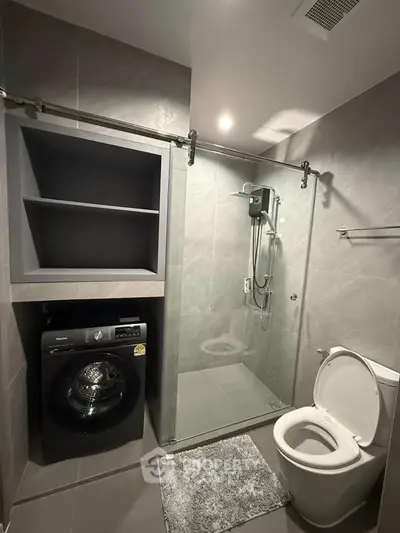 Modern bathroom with glass shower, washing machine, and sleek design.