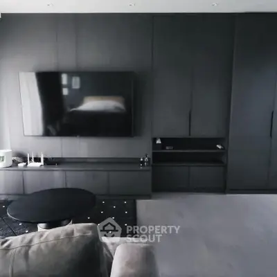 Modern living room with sleek black cabinetry and large flat-screen TV.