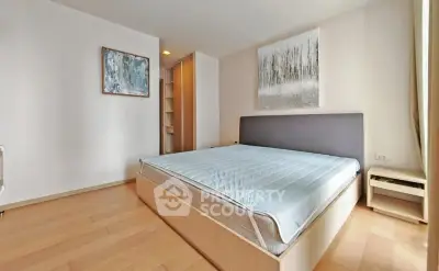 Spacious bedroom with modern decor and natural light, featuring a comfortable bed and stylish artwork.