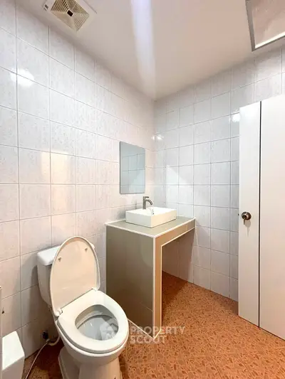 Modern bathroom with sleek sink and tiled walls, featuring a contemporary design and functional layout.