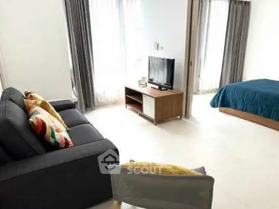 Modern open-plan living room with cozy sofa and TV, leading to a bright bedroom with large windows.