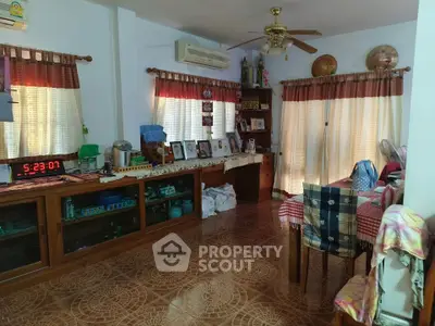 Cozy living room with tiled floor, wooden furniture, and natural light through large windows.