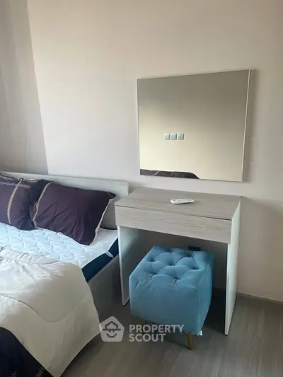 Cozy bedroom with modern vanity and plush blue ottoman, perfect for relaxation.