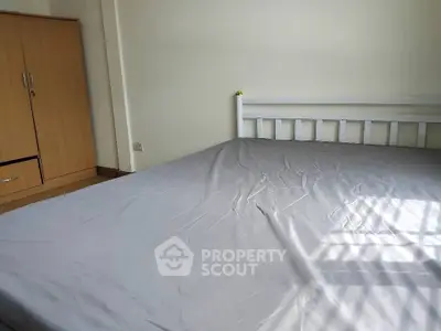 Spacious bedroom with natural light and wooden wardrobe