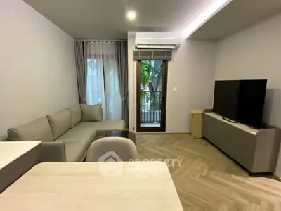 Modern living room with sleek furniture and large TV, featuring a cozy balcony view.
