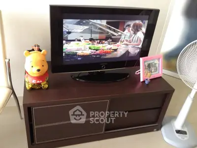 Cozy living room corner with TV, fan, and decorative items on a stylish cabinet.