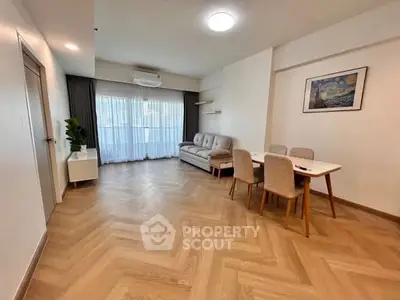 Spacious living room with elegant herringbone flooring and modern furniture in a bright apartment.