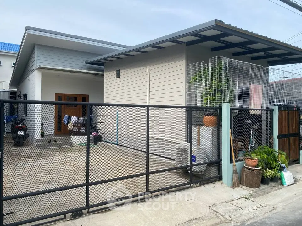 Modern single-story house with gated driveway and minimalist design.