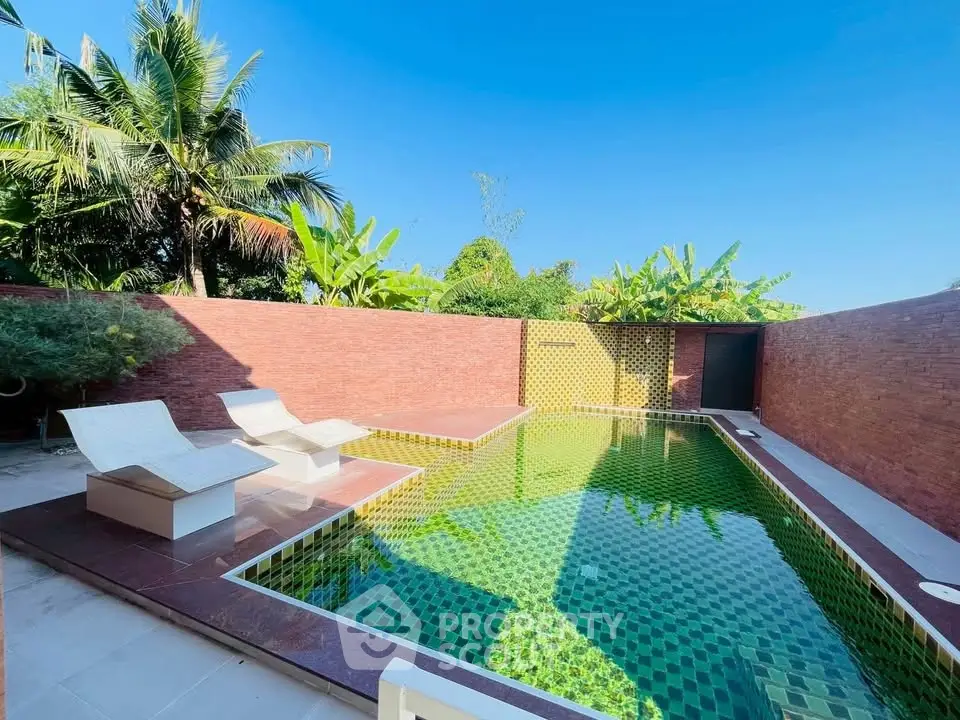 Luxurious private pool with tropical garden and sun loungers, perfect for relaxation.