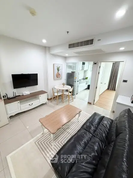 Modern living room with sleek furniture and open kitchen layout in a stylish apartment.