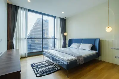Modern bedroom with large window and city view, featuring stylish bed and wooden flooring.