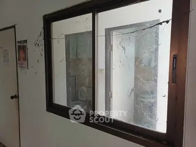 Dilapidated interior with broken window and visible bathroom, ideal for renovation enthusiasts.