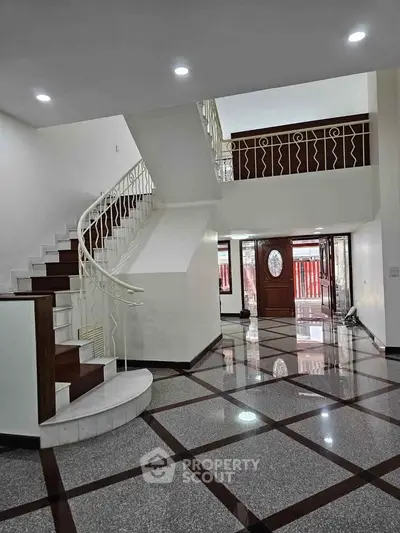 Elegant entrance with modern staircase and glossy tiled flooring in a spacious home