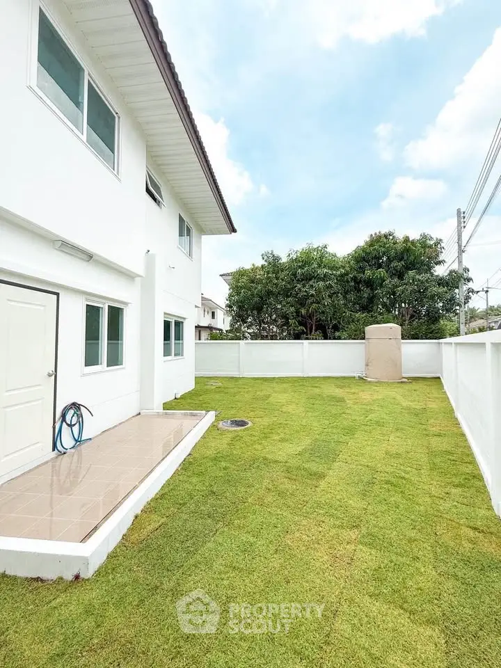 Spacious backyard with lush green lawn and modern white exterior, perfect for outdoor activities.