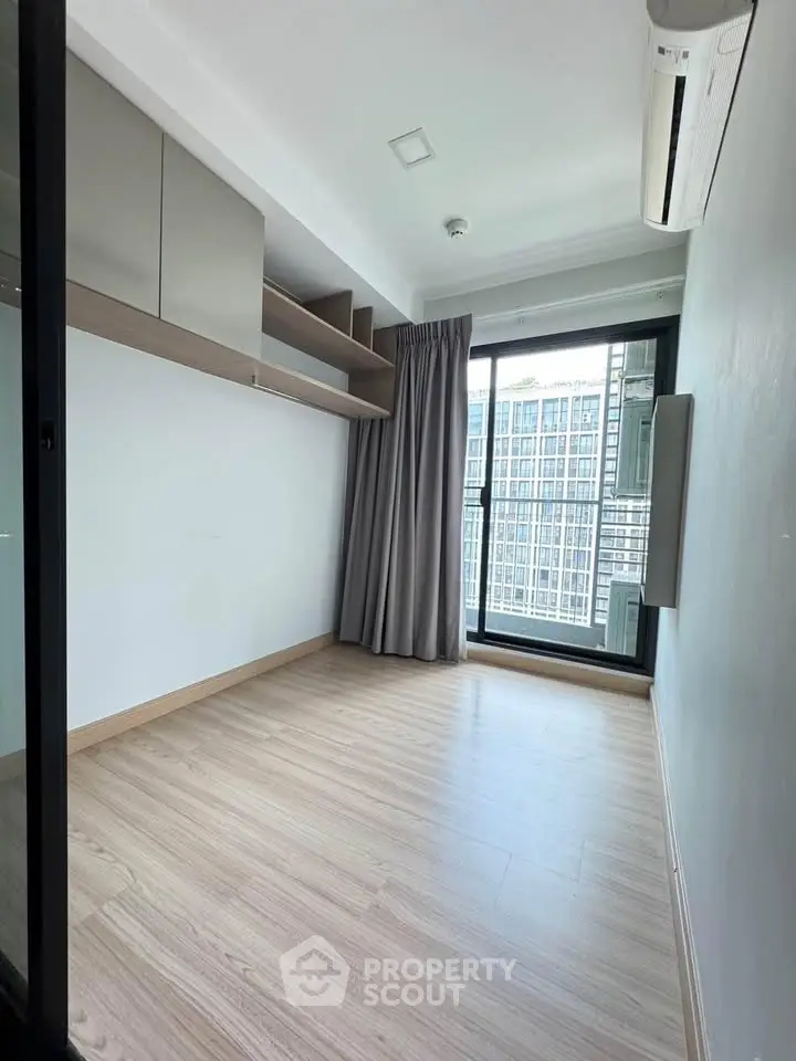 Modern minimalist room with large window and city view, featuring built-in shelves and air conditioning.