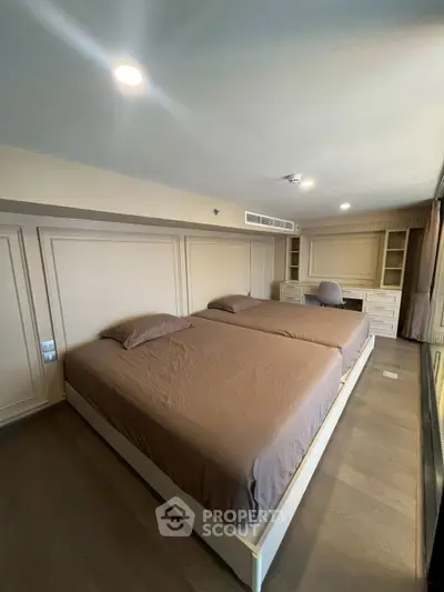 Spacious bedroom with twin beds and built-in desk, perfect for modern living.