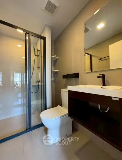 Modern bathroom with glass shower and sleek fixtures in a contemporary apartment.