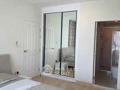 Modern bedroom with mirrored closet and ensuite bathroom in a stylish apartment.