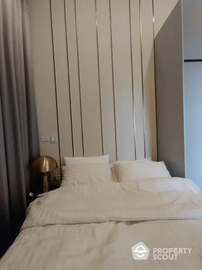 Elegant bedroom with plush white bedding and stylish vertical panel wall design, complemented by chic golden bedside lamp.