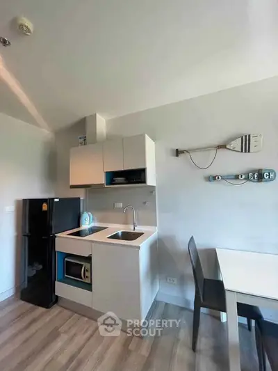 Modern compact kitchen with sleek cabinetry and dining area in a cozy apartment setting.