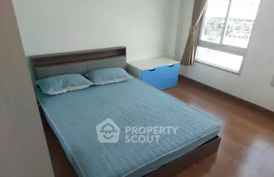 Cozy bedroom with wooden flooring and large window for natural light