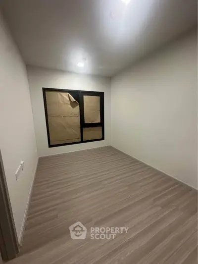 Spacious empty room with modern flooring and large window, perfect for customization.