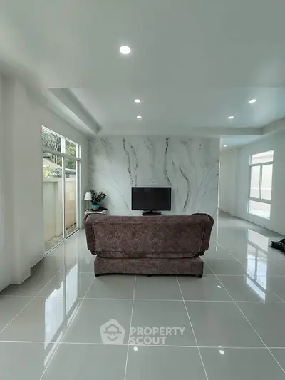 Modern living room with sleek marble accent wall and large windows for natural light.