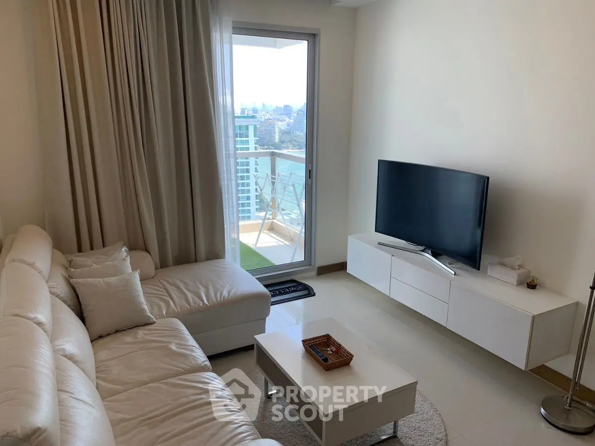 Modern living room with white sofa, TV, and balcony view in high-rise apartment.