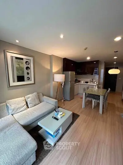 Modern living room with open kitchen, stylish decor, and cozy seating area.